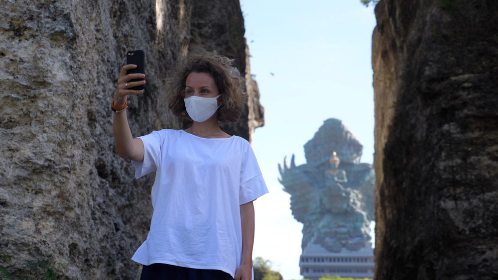 Seorang wisatawan mancanegara yang sudah menerapkan protokol kesehatan, tengah berswafoto di kawasan Garuda Wisnu Kencana, Bali. (Foto: Shutterstock/Sia Footage)